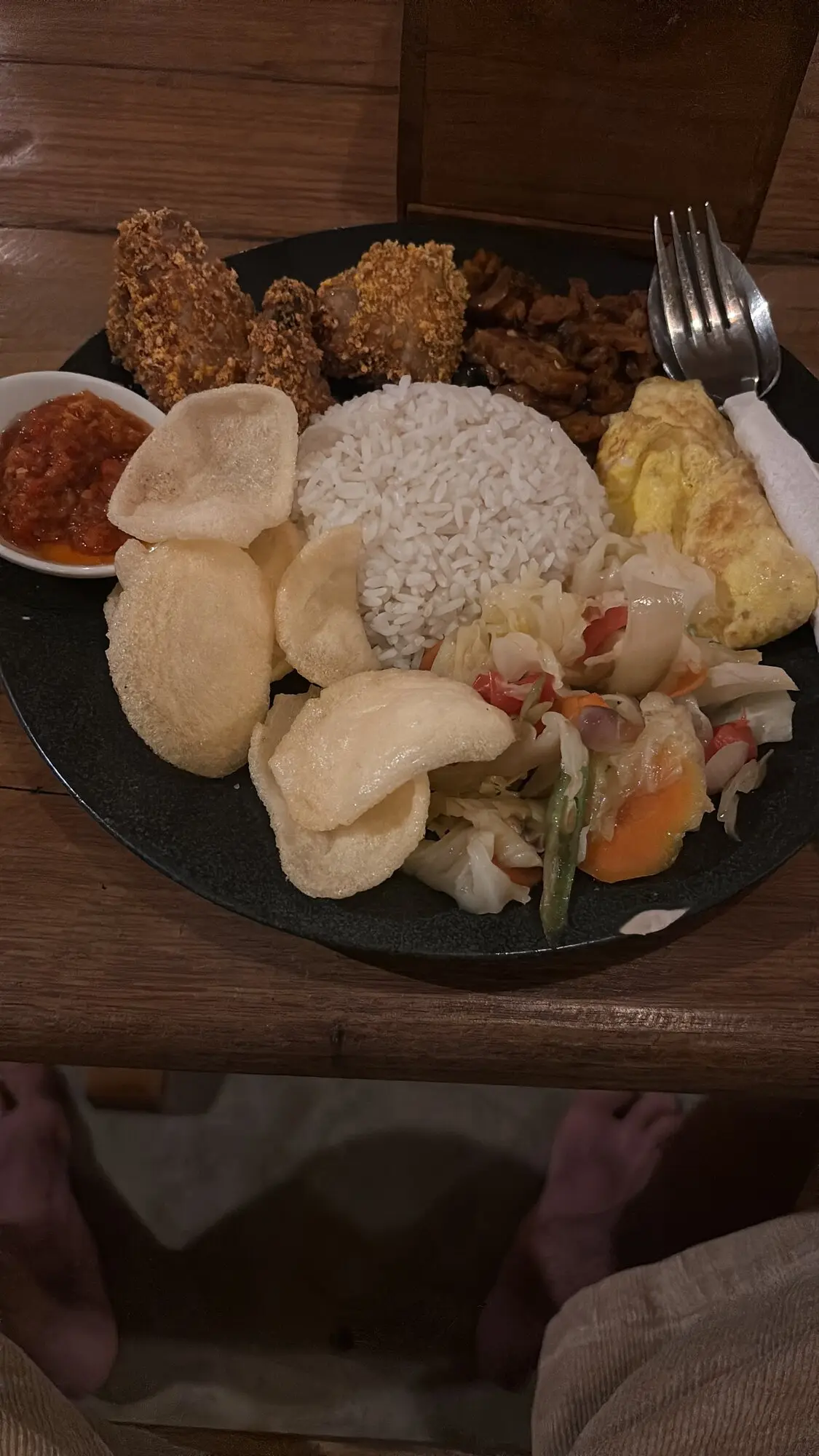 Plate of nasi campur with fried chicken, rice, prawn crackers, vegetables, omelette and sambal at a local Sumbawa restaurant