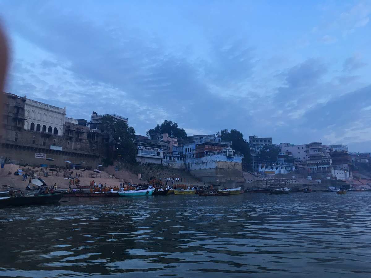 Wide view of the Varanasi riverfront with boats moored along the Ganges at dusk