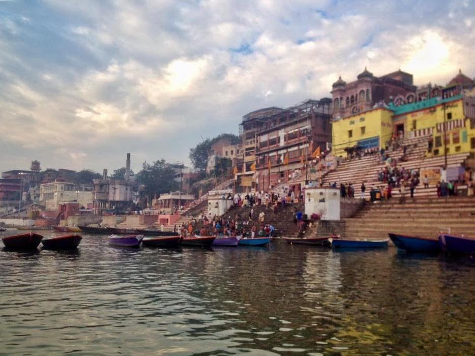 Varanasi ghats with colorful wooden boats on the Ganges and ancient buildings under dramatic clouds