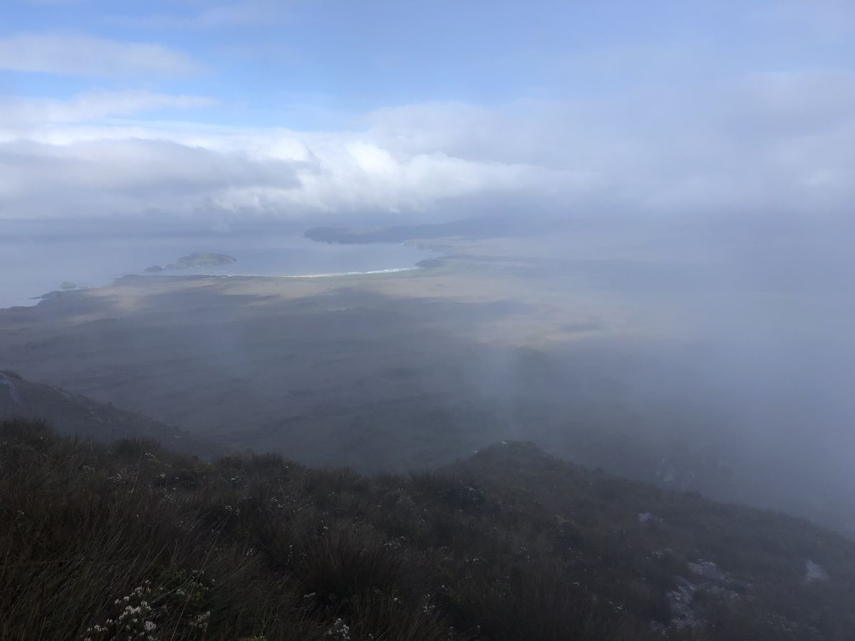 Misty view from Ironbound Range summit looking down through cloud to the coastline far below