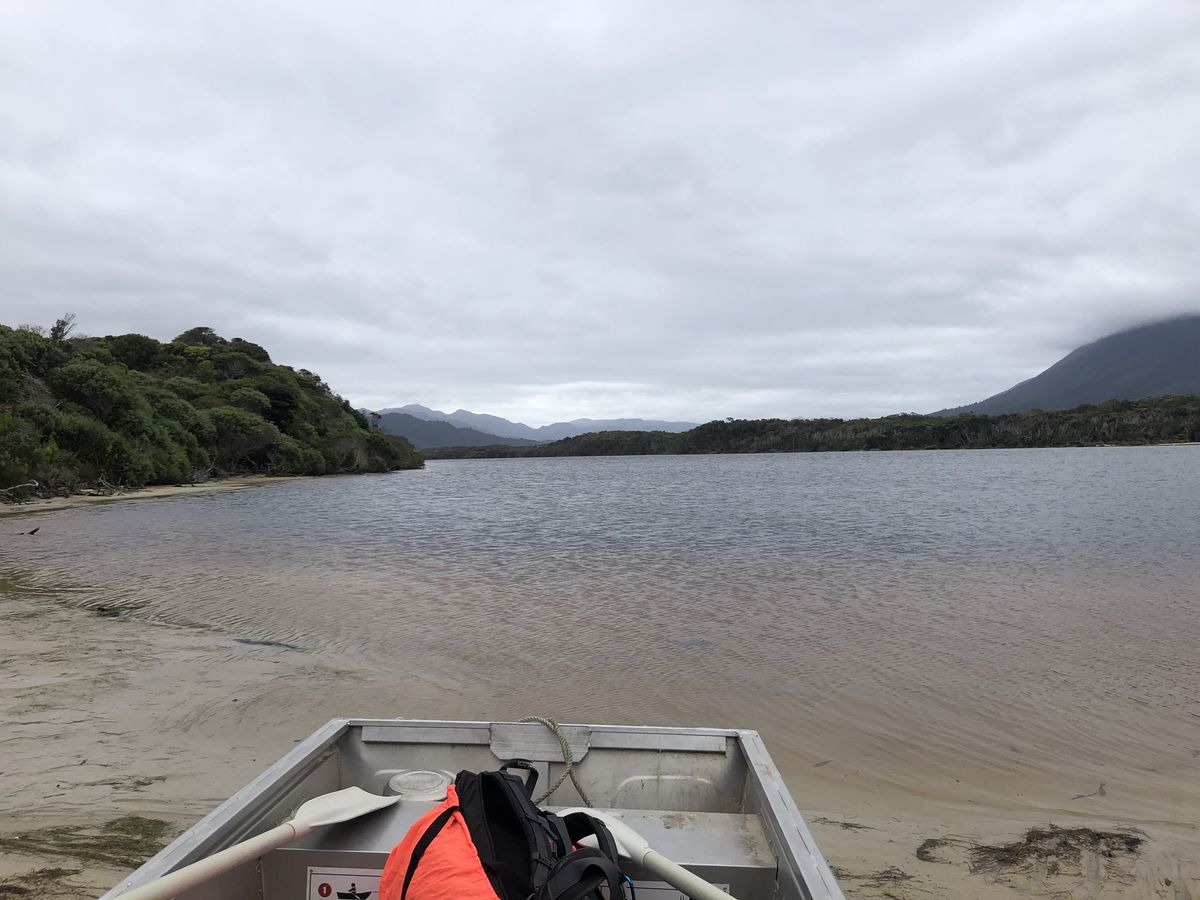 Aluminium boat on tannin-stained river with mountains in mist and life jacket visible